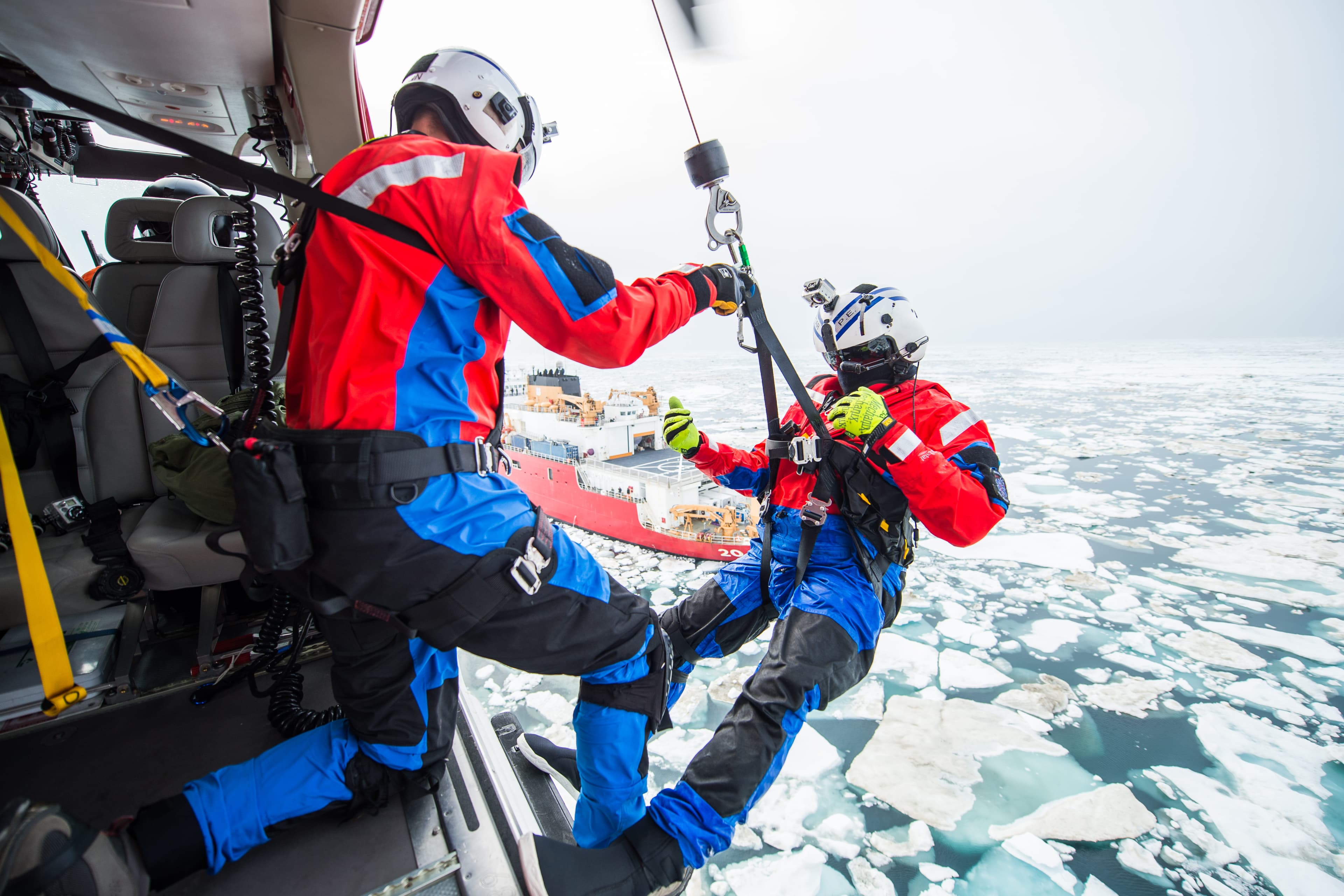 Arctic hoist from helicopter over ice with ship in background